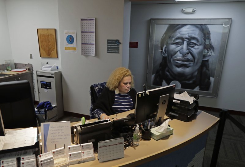 Nia Tagoai, a patient scheduler at a clinic offering health care and other services operated by the Seattle Indian Health Board, works at her desk Friday, Jan. 11, 2019, in Seattle. (AP Photo/Ted S. Warren)