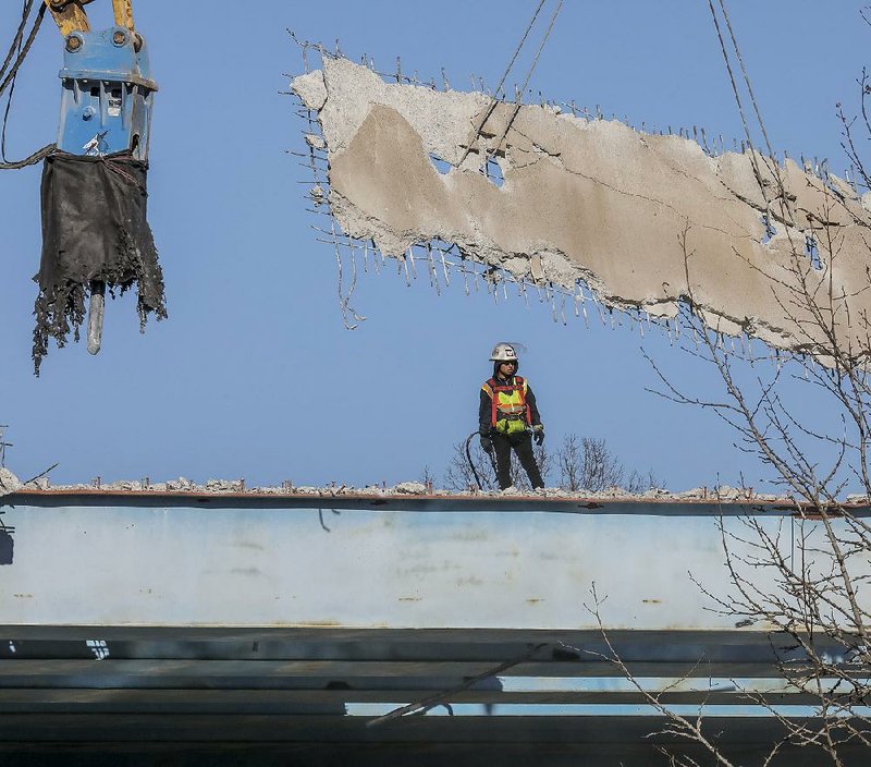 Arkansas Democrat-Gazette/JOHN SYKES JR. - In this Dec. 28 photo, a workman an watches as a large piece of the roadway of the Interstate 630 overpass at South Rodney Parham Road is removed in Little Rock. 