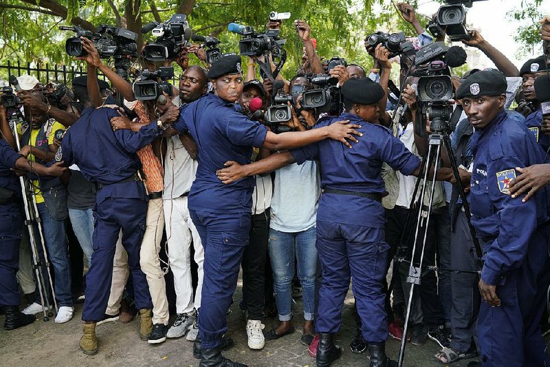 Congolese police officers hold back members of the media Saturday as Martin Fayulu, a candidate in last month’s presidential election, leaves the constitutional court in Kinshasa. 