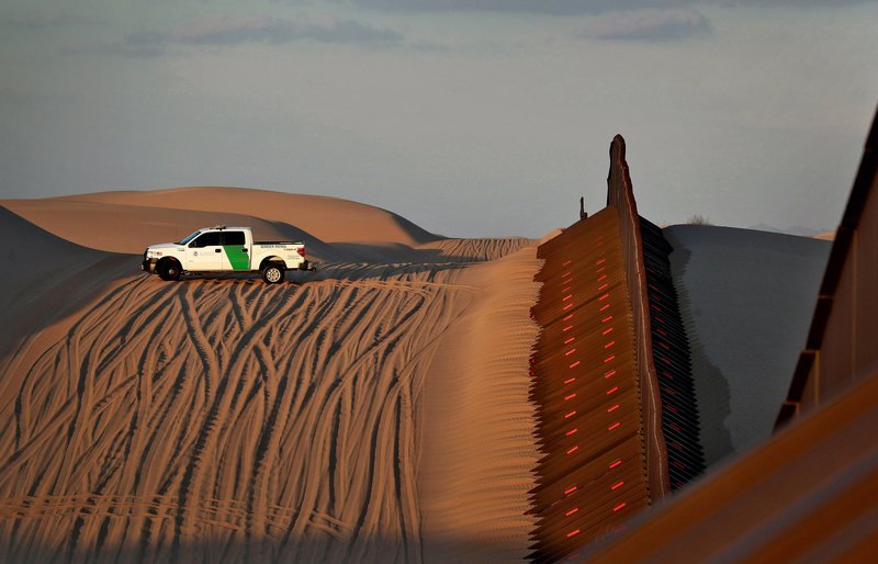 FILE - In this July 18, 2018 file photo, a U.S. Customs and Border Patrol agent patrols a section of floating fence at sunset that runs through Imperial Sand Dunes along the international border with Mexico in Imperial County, Calif. President Donald Trump is not giving up on his demands for $5.7 billion to build a wall along the U.S.-Mexico border, saying a physical barrier is central to any strategy for addressing the security and humanitarian crisis at the southern border. Democrats argue that funding the construction of a steel barrier along roughly 234 miles will not solve the problems. (AP Photo/Matt York, File)