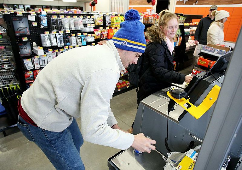 Bo Warner (left) and May Silzer, freshmen at the University of Arkansas, use a self-checkout station at the Walmart On Campus in Fayetteville. The remodeled store opened Monday. 