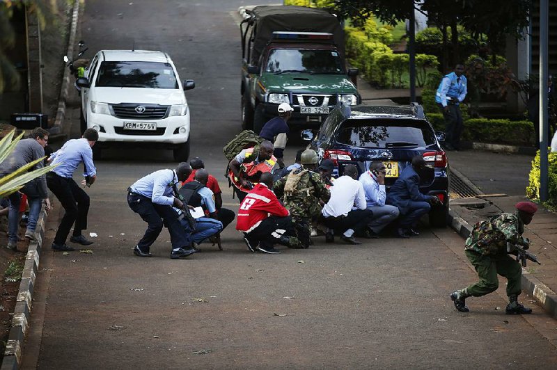 People take cover Tuesday in Nairobi, Kenya, after extremists stormed a luxury hotel in a deadly attack that left a scene of bodies, blood, broken glass and fires. Officials said the area was secured about eight hours after the siege began. The Somalia-based Islamic militant group Al-Shabab claimed responsibility for the assault. 