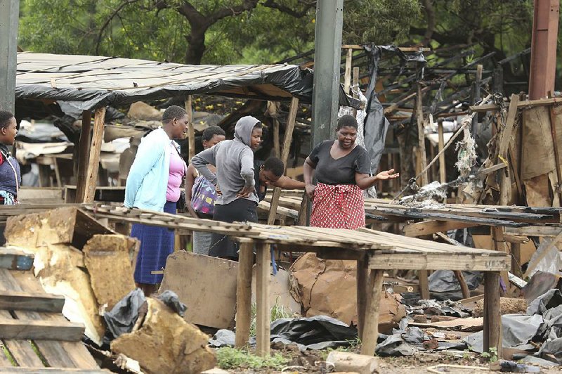 Zimbabwean women inspect what remains of their stalls at a market in Harare on Tuesday. Residents damaged  the market during protests over fuel-price increases. 