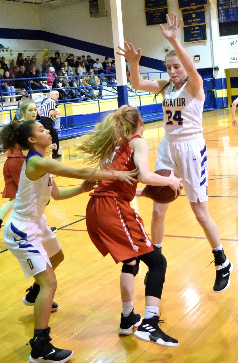 Westside Eagle Observer/MIKE ECKELS Lady Bulldogs Desi Meek (left) and Sammie Skaggs (Decatur 24) hem in Haylee Marberry (Flippin 15), preventing her from passing the ball off to teammates during the Decatur-Flippin basketball game in Decatur Jan. 11.