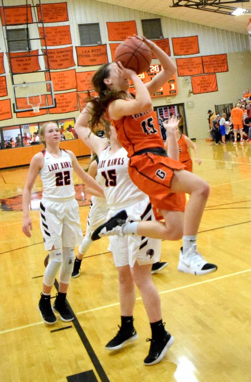 Westside Eagle Observer/MIKE ECKELS Gravette's Shylee Morrison (15) flys past Blakelee Winn (Lady Hawks 22) and Maria Socha (Lady Hawks 15) on her way to the basket for a layup late in the fourth quarter of the Gravette-Pea Ridge basketball contest in Gravette Jan. 11.