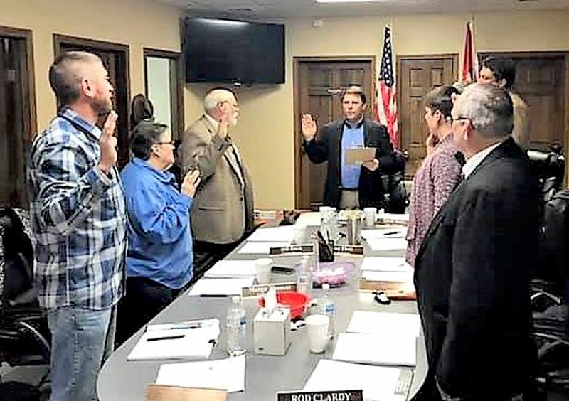 Submitted Photo/MALLORY WEAVER Gravette Mayor Kurt Maddox swears in the 2019 city council members at their Committee of the Whole meeting Thursday, Jan. 10, at City Hall. Pictured are James Brown (left), Margo Thomas, Jeff Davis, Mayor Maddox, Ron Theis (not visible), Ashley Harris and Rod Clardy. City attorney David Bailey is in the background at right.