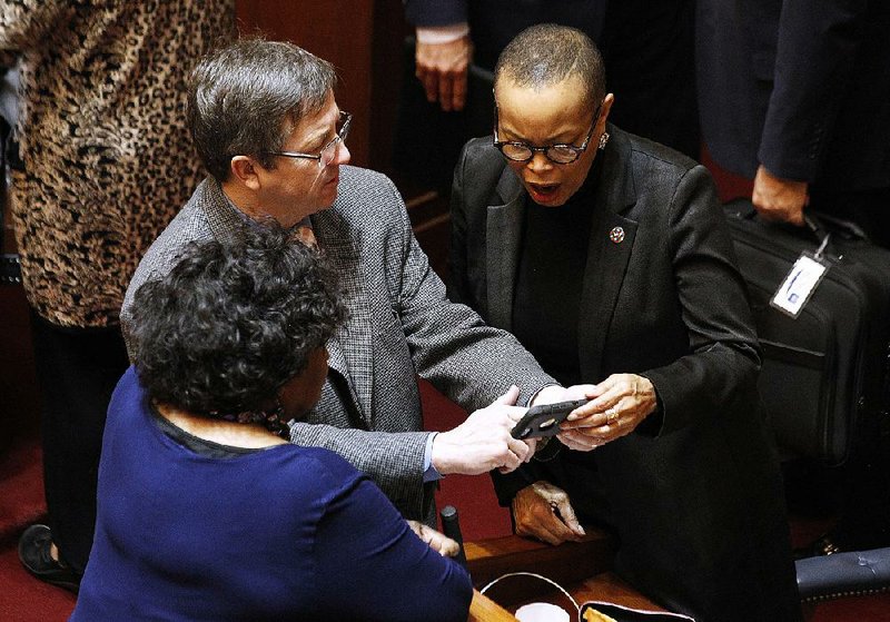 Sen. Larry Teague, D-Nashville, shows phone pictures to Sen. Joyce Elliott (right) and Sen. Linda Chesterfield, both Democrats from Little Rock, at the end of Wednesday’s Senate session. 