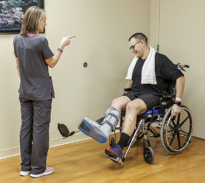 Physical therapist Meredith McKelvy gives instruction Wednesday to Paul Sanchez, 22, at the Baptist Health Rehabilitation Institute in Little Rock. Sanchez, an emergency medical technician, was injured when his ambulance was struck head-on earlier this month on Interstate 40. 