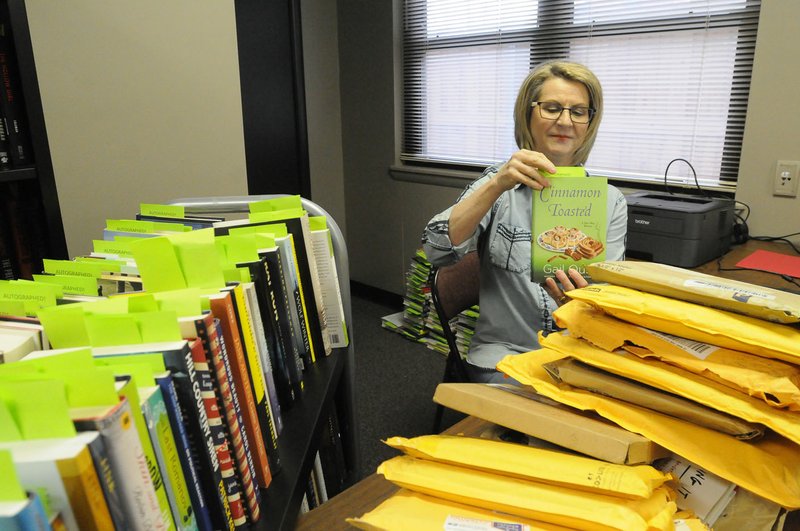 File Photo/FLIP PUTTHOFF Cherie Geiser, a volunteer with the Benton County Literacy Council, sorts through some of the donated books that were sold at auction during the Scrabble Wars fundraiser. The 2019 benefit will be Jan. 26 at DoubleTree Suites by Hilton in Bentonville.