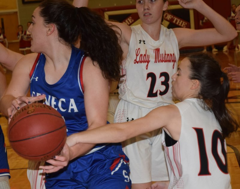 RICK PECK/SPECIAL TO MCDONALD COUNTY PRESS McDonald County's Lily Allman knocks the ball loose from Seneca's Haley Miller during the Lady Mustangs 44-31 loss on Jan. 11 at MCHS.