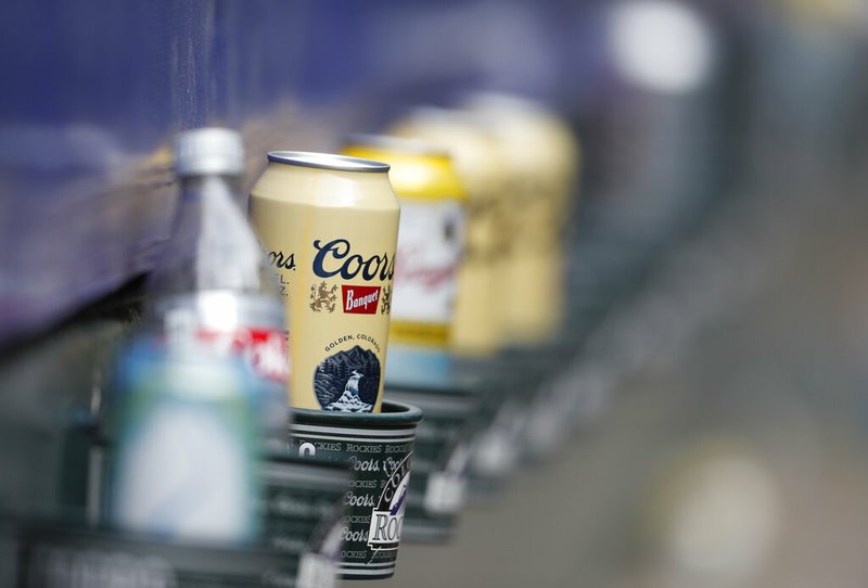 FILE- In this June 3, 2018, file photo empty cans of Coors beer sit in beverage holders on the backs of box seats after the ninth inning of a baseball game in Denver. The makers of Budweiser, Coors and other large-scale brewers are placing their bets on cannabis as a way to fight saturated markets and shifting consumer trends. (AP Photo/David Zalubowski, File)