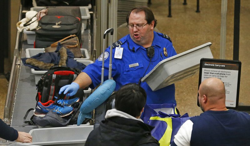 A TSA worker helps passengers at the Salt Lake City International Airport Wednesday Jan., 16, 2019, in Salt Lake City. The government shutdown has generated an outpouring of generosity to TSA agents and other federal employees who are working without pay. In Salt Lake City, airport officials treated workers from the TSA, FAA and Customs and Border Protection to a free barbecue lunch as a gesture to keep their spirits up during a difficult time. (AP Photo/Rick Bowmer)