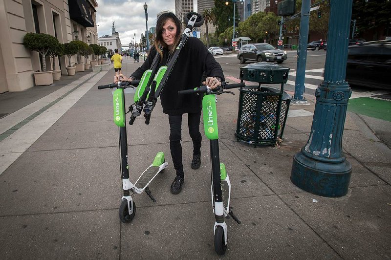 Livia Looper, who works for LimeBike, moves some of the scooters in San Francisco. 