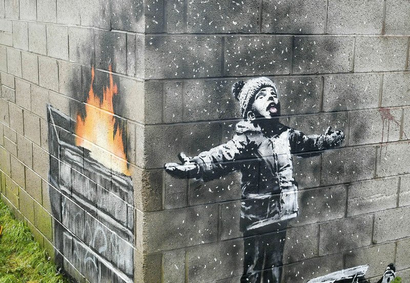 In this file photo dated Dec, 20, 2018, showing an artwork by Banksy on the side of a garage depicts a child dressed for snow playing in the falling ash and smoke from a skip fire, in Port Talbot, Wales. The artwork has been sold to an Essex art dealer for a "six-figure sum", although the mural will stay in its current location for about two-years, it is revealed Friday Jan. 18, 2019. (Ben Birchall/PA FILE via AP)