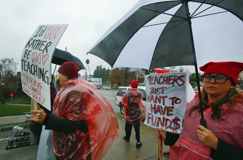 Teachers, parents and students picket under the rain in downtown Los Angeles Thursday, Jan. 17, 2019. A new round of contract negotiations began between Los Angeles school district officials and a teachers union as thousands of educators picketed in the rain. The announcement that the two sides were sitting down Thursday for the first time in nearly a week didn't indicate whether any new contract offers would be on the table. Union officials tempered expectations, saying a quick deal was unlikely. District officials have said teacher demands could bankrupt the school system. (AP Photo/Damian Dovarganes)