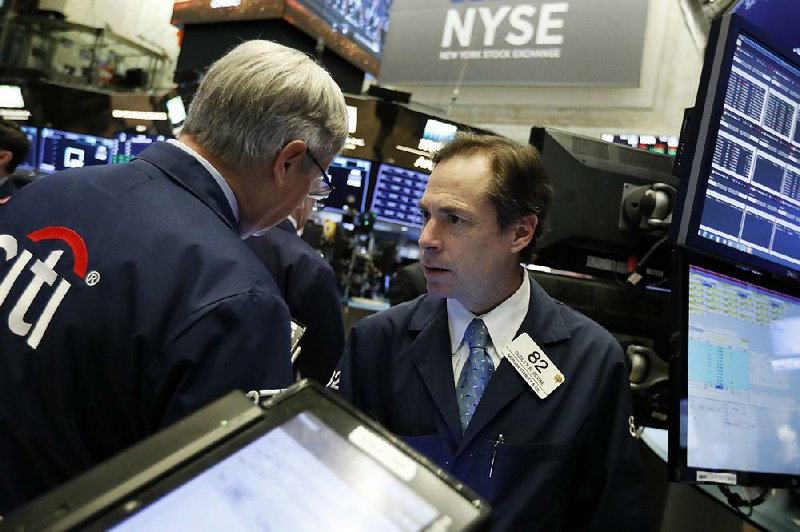 Trader Dudley Devine (right) works Friday on the floor of the New York Stock Exchange. 