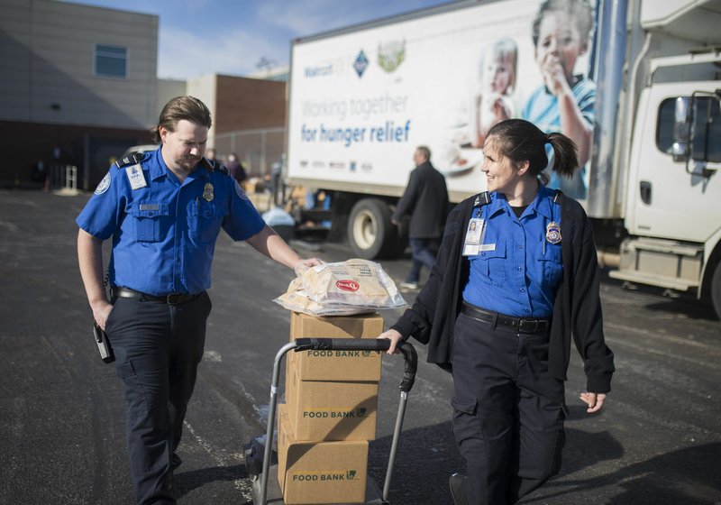 Dennis Weeks (left) and Sydney Johnson with the Transportation Security Administration pull a cart loaded with food Friday at Northwest Arkansas Regional Airport in Highfill. 