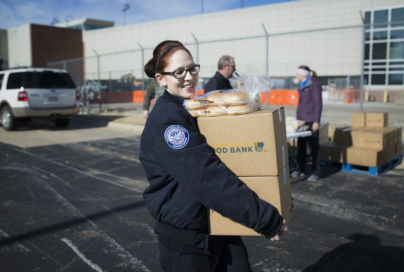 Transportation Security Administration screener Terisa Flippin carries boxes of donated food Friday at Northwest Arkansas Regional Airport in Highfill.