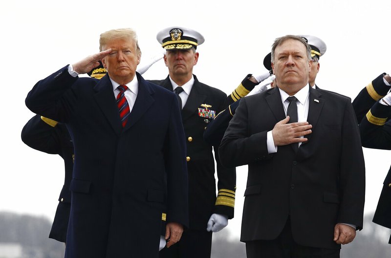 President Donald Trump, left, and Secretary of State Mike Pompeo stand at attention as they await a U.S. Navy carry team moving a transfer case containing the remains of Scott A. Wirtz, Saturday, Jan. 19, 2019, at Dover Air Force Base, Del. According to the Department of Defense, Wirtz, a civilian and former Navy SEAL from St. Louis, Mo., was killed Jan. 16, 2019, in a suicide bomb attack in Manbij, Syria. (AP Photo/Patrick Semansky)