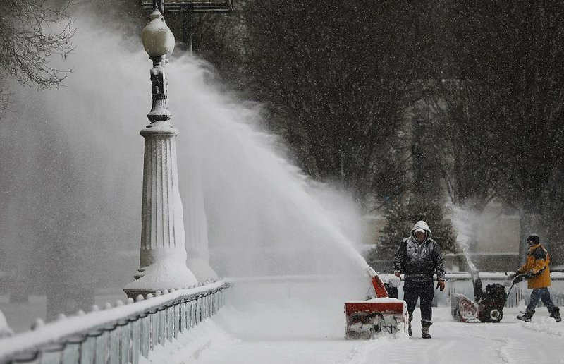 People clear the snow from the skating rink Saturday at Millennium Park in Chicago. 