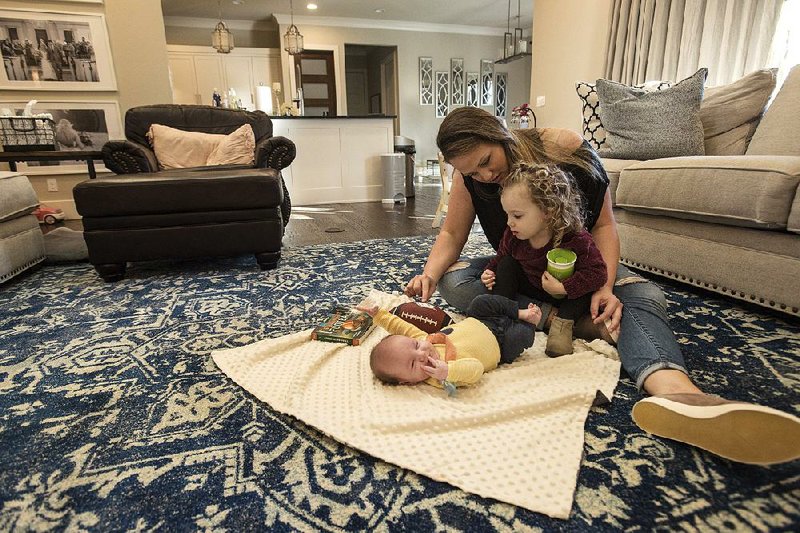 Abby Craddock, wife of Arkansas offensive coordinator Joe Craddock, plays with her daughter Charlie, 2, and son Cain, 10 weeks, on Friday in their home in Fayetteville.