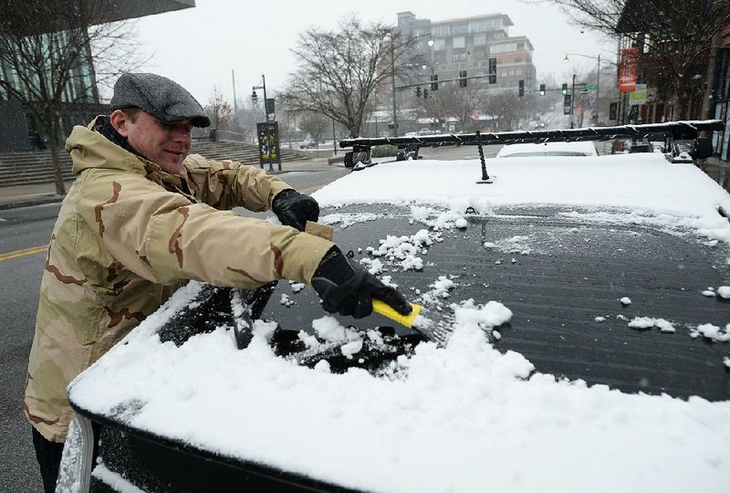 Stephen Fowler of Fayetteville scrapes snow from his rear windshield Saturday on Dickson Street in Fayetteville.