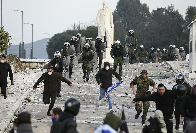 Greek riot police chase demonstrators Sunday during clashes after a rally in Athens.