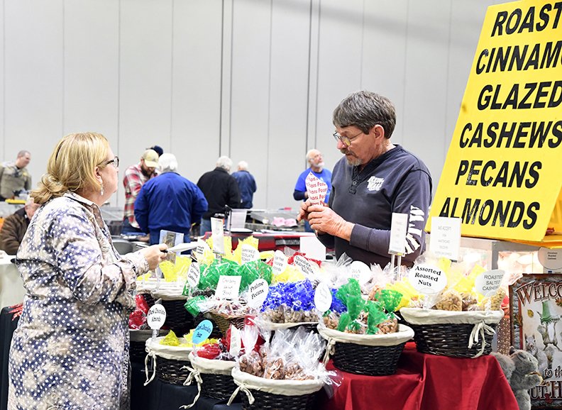 The Sentinel-Record/Grace Brown - John Thompson, right, of Little Rock packs up a fresh bag of roasted pecans while speaking to Donna Cox of Little Rock during the Lions Club Gun Show at the Hot Springs Convention Center on Sunday, January 20, 2019. 