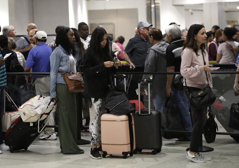 FILE- In this Jan. 18, 2019, file photo passengers wait in line at a security checkpoint at Miami International Airport in Miami. While security screeners and air traffic controllers have been told to keep working, Federal Aviation Administration safety inspectors weren&#x2019;t, until the agency began recalling some Jan. 12. About 2,200 of the more than 3,000 inspectors are now back on the job, overseeing work done by airlines, aircraft manufacturers and repair shops. The government says they&#x2019;re doing critical work but forgoing such tasks as issuing new pilot certificates.(AP Photo/Lynne Sladky, File)