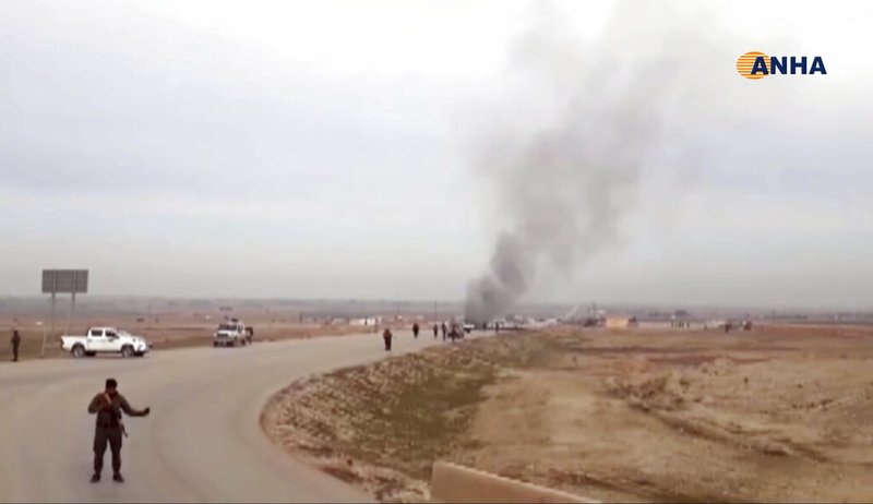 This frame grab from video provided by Hawar News, ANHA, the news agency for the semi-autonomous Kurdish areas in Syria, shows Kurdish fighters standing guard at the site of a suicide attack near the town of Shaddadeh, in Syria's northeastern province of Hassakeh, Syria, Monday, Jan. 21, 2019. The state news agency SANA and the Kurdish Hawar news agency, said that the blast was a suicide bombing that targeted a Syrian Kurdish checkpoint. (ANHA via AP)