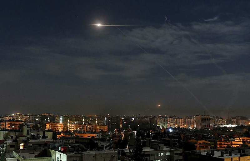 This photo, released by the state-run Syrian Arab News Agency, shows missiles flying into the sky near the international airport in Damascus, Syria, on Monday. 