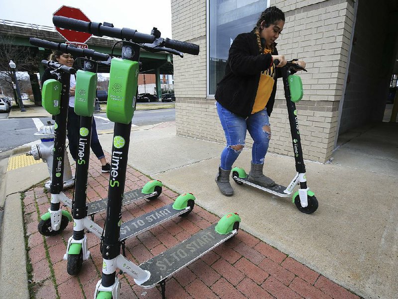 FILE — Kimberly Rivera (right) and Cristal Martinez rent scooters in the Little Rock River Market District on Jan. 22, 2019. Little Rock began a six-month pilot program with scooter company Lime earlier this month.   