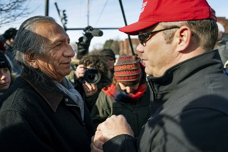 Guy Jones (left) joins hands with a supporter of President Donald Trump, who gave his name as Don, during a gathering of American Indian supporters Tuesday outside the Roman Catholic Diocese of Covington, Ky. 