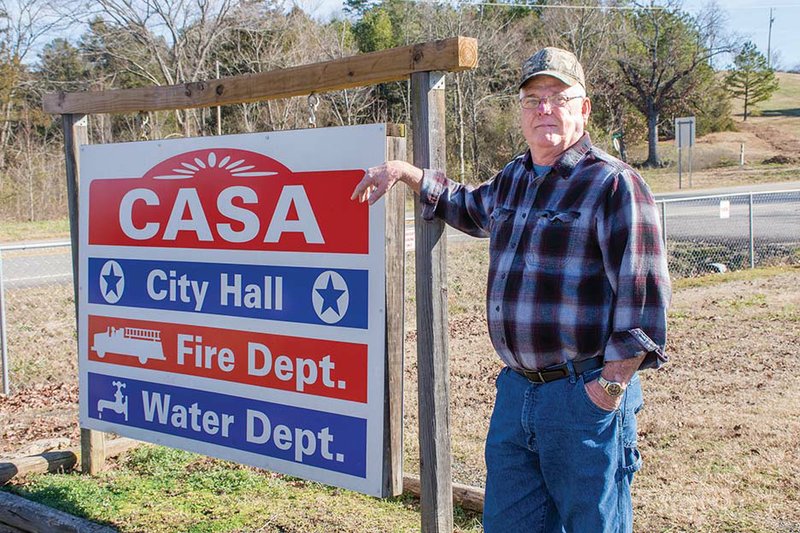 New Casa Mayor Gary Rainey stands by a sign in the small Perry County community. A plumber for decades, Rainey said he decided to use his talents to help the town improve its water system, and he hopes to bring in new businesses.