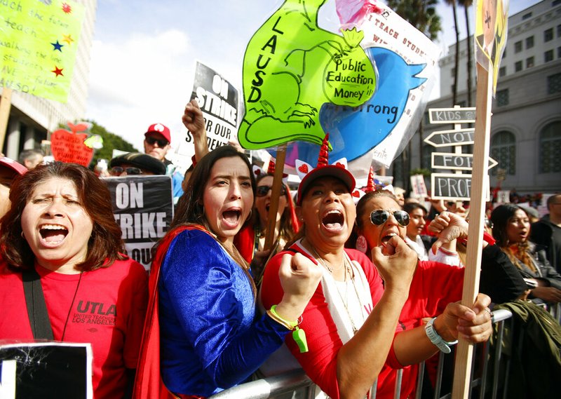 In this Friday, Jan. 18, 2019 file photo, elementary school teachers Iris Marin, center, and Mireya Gutierrez, right, and Lorena Redford, clench fists at a rally in downtown Los Angeles. Los Angeles teachers who declared a victory after a six-day strike have added momentum to a wave of activism by educators. They've tapped a common theme and found success by framing their cause as a push to improve public education, not just get pay raises. (AP Photo/Damian Dovarganes, File)