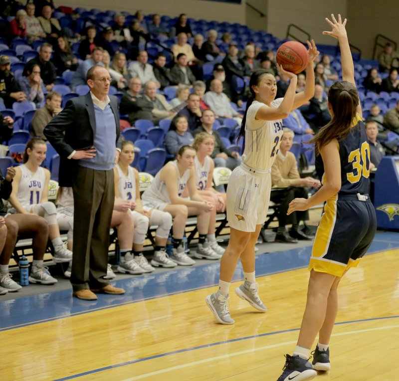 Photo courtesy of John Brown University John Brown senior Karina Chandra launches a 3-pointer in front of the JBU bench as Texas Wesleyan's Nicole Gleason defends during the second half Thursday at Bill George Arena. Texas Wesleyan defeated the Golden Eagles 72-64.