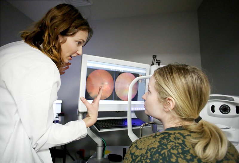 NWA Democrat-Gazette/DAVID GOTTSCHALK Dr. Emma Hendricks (left) explains to Aubrey Bland the results of her glaucoma screening Jan. 10 at Vold Vision at the Sam's Club in Springdale. The test photographs the optic nerve in the retna of the eye. January is Glaucoma Awareness Month and Vold Vision is providing free glaucoma screenings.