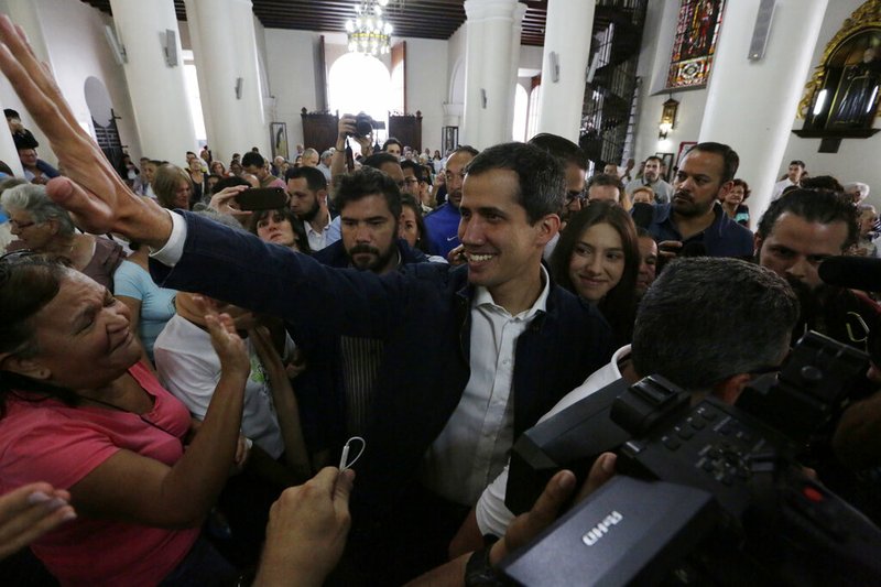 Opposition National Assembly leader Juan Guaido, who declared himself interim president, greets supporters as he arrives to attend Mass at a church in Caracas, Venezuela, Sunday, Jan. 27, 2019. Guaido says he is acting in accordance with two articles of the constitution that give the National Assembly president the right to hold power temporarily and call new elections. (AP Photo/Fernando Llano)
