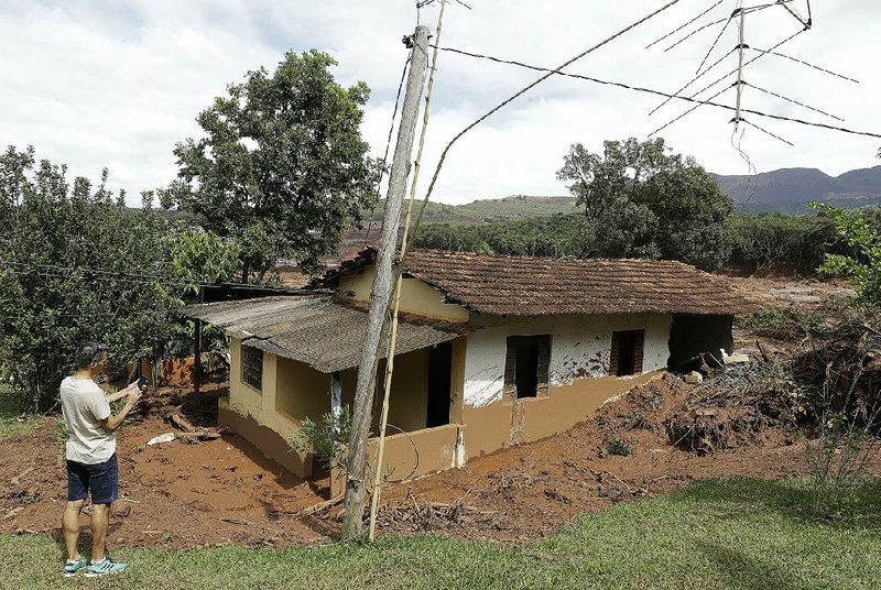 A man takes a picture Sunday outside a damaged home that was evacuated after the dam collapse in Brumadinho, Brazil. 