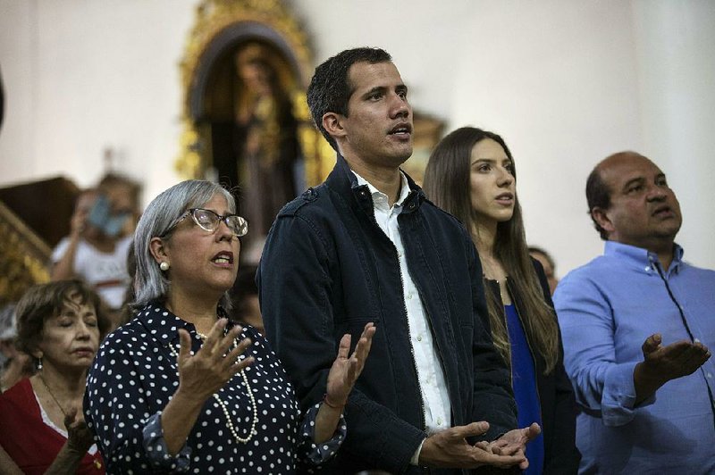 Juan Guaido, the National Assembly leader who has proclaimed himself president of Venezuela, prays next to his wife, Fabiana Rosales (second from right), on Sunday at a church in Caracas. 