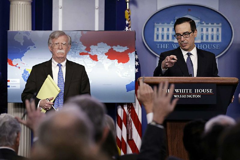 John Bolton (left), the national security adviser, listens Monday as Treasury Secretary Steven Mnuchin takes questions from reporters during a briefi ng at the White House in which President Donald Trump’s administration announced sanctions on Venezuela’s national oil company. 