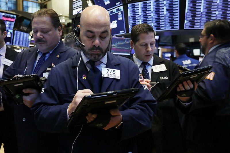 Fred DeMarco (foreground) works with fellow traders Monday on the floor of the New York Stock Exchange. Stocks fell after Caterpillar and Nvidia blamed China’s slowing economic growth for disappointing results. 