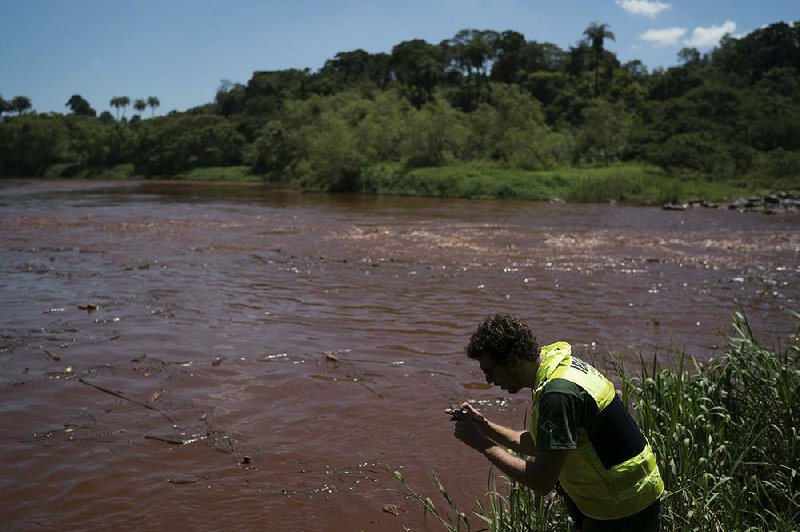 A member of the Brazilian Environmental Institute takes pictures Tuesday of the Paraopeba River after Friday’s collapse of the mining company dam in Brumadinho, Brazil.