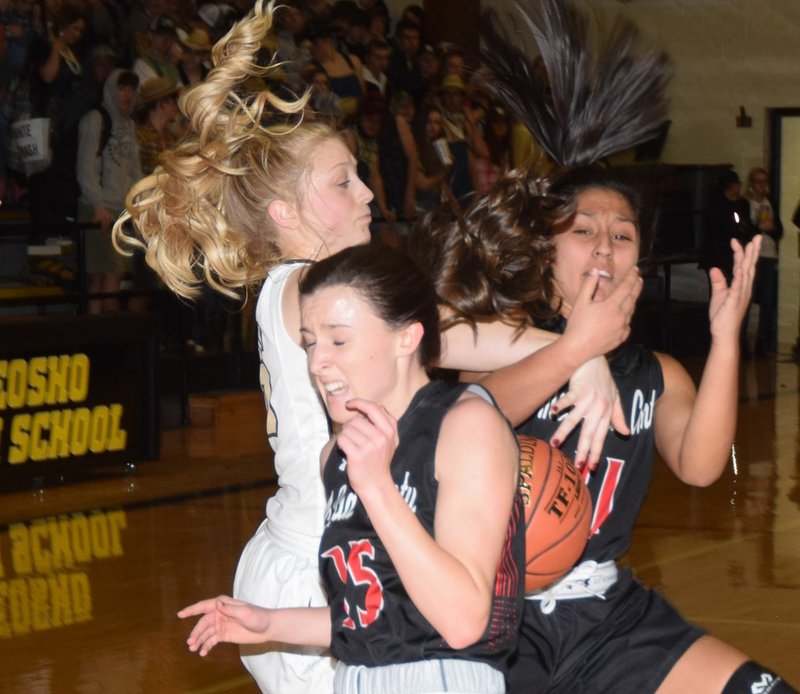 RICK PECK/SPECIAL TO MCDONALD COUNTY PRESS McDonald County's Ragan Wilson (15) and Rita Santillan (11) battle with Neosho's Olivia Hixson during the Lady Wildcats' 46-42 win on Jan. 25 at Neosho High School.