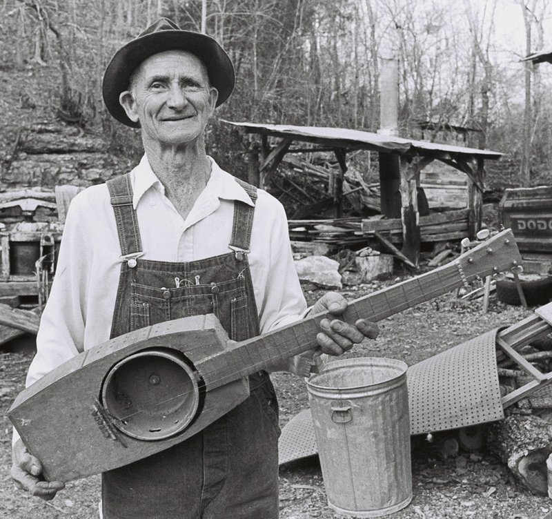 Courtesy Photo/Flip Putthoff Ed Stilley, who spent his life building handmade instruments for children near Hogscald Holler, poses with one of his guitars. Stilley is the subject of an exhibit opening Monday at the Shiloh Museum in Springdale. ON THE COVER Courtesy Photo/Flip Putthoff Ed Stilley, who spent his life building handmade instruments for children near Hogscald Holler, Ark., poses with one of his guitars late in his body of work. Stilley is the subject of Kelly Mulhollan's new book, &quot;True Faith, True Light: The Devotional Art of Ed Stilley.&quot;
