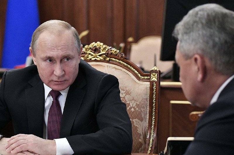 Russian President Vladimir Putin talks with Russian Defense Minister Sergei Shoigu during a meeting Saturday at the Kremlin. Putin said Russia won’t be drawn into an expensive arms race. 