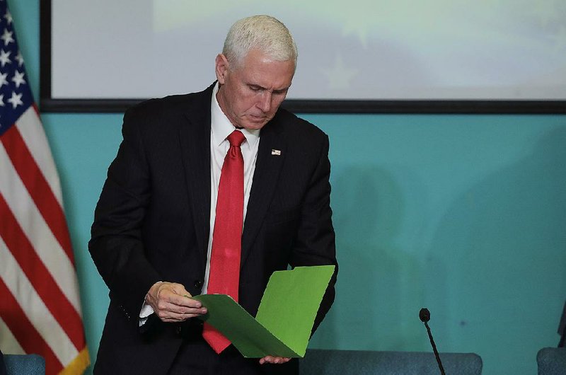 Vice President Mike Pence looks at a folder of recommendations from a group of Venezuelan exiles Friday in Doral, Fla., during a discussion about Venezuela’s political crisis. 
