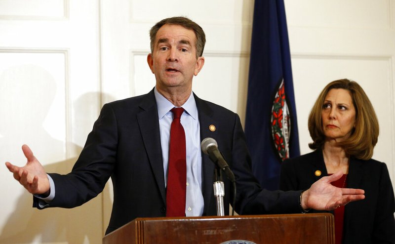 Virginia Gov. Ralph Northam, left, gestures as his wife, Pam, listens during a news conference in the Governors Mansion at the Capitol in Richmond, Va., Saturday, Feb. 2, 2019. Northam is under fire for a racial photo that appeared in his college yearbook. (AP Photo/Steve Helber)