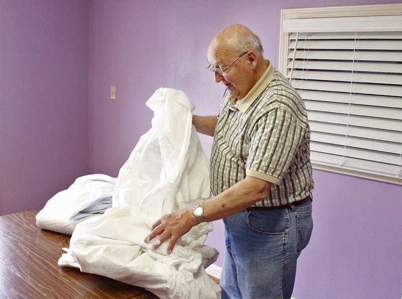 Hope: Mervin Mast gathers up a table covering after finishing painting a new art room Tuesday at HOPE Landing. Mast is one of a group of volunteers from northern Indiana who are staying in the area and giving their time to local organizations. Madeleine Leroux/News-Times