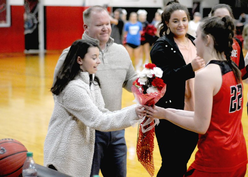 MARK HUMPHREY ENTERPRISE-LEADER/Miracle girls meet. Farmington junior basketball star Makenna Vanzant (right) presents a bouquet of roses to Pea Ridge cheerleader Kennedy Allison, who recently returned to school after collapsing in a classroom Friday, Jan. 11. School personnel including principal and former head boys basketball coach Charley Clark, head baseball coach John King, and school nurse LaRay Thetford, began CPR and used a defibrillator to get Kennedy's heart beating again. In October of 2017, Vanzant was unexpectedly hospitalized for 16 days battling for her life against Hemolytic Uremic Syndrome. When Vanzant made a miraculous return to basketball, Pea Ridge players each gave her flowers before a Dec. 8, 2017 game during the Tony Chachere's tournament. Farmington returned the gesture prior to a Tuesday, Jan. 29 conference game between the schools won by Pea Ridge, 63-60, in overtime.